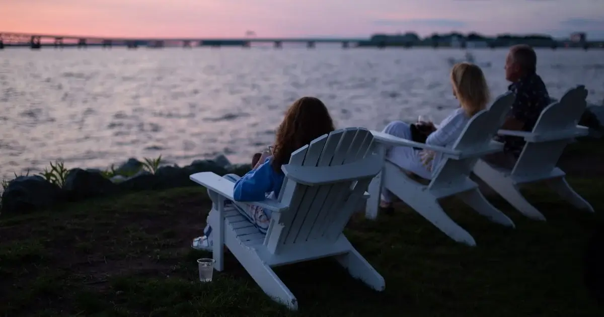 Group relaxing in Adirondack chairs by the waterfront